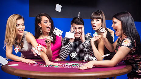 Un gruppo di ragazzi su un tavolo del Blackjack Party lanciano in aria delle carte con fare sbarazzino.