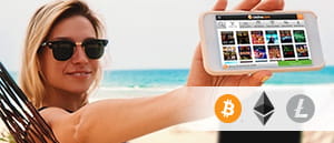 Una donna con in mano uno smartphone e i loghi delle criptovalute Bitcoin, Litecoin ed Ethereum.