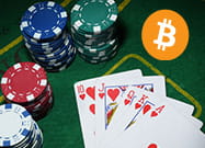 Alcune fiche, delle carte da gioco e il logo di Bitcoin.